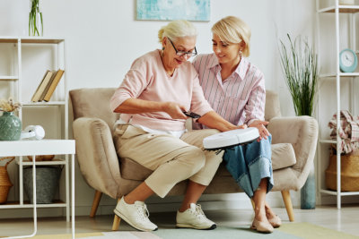 woman smiling while taking care of the senior woman