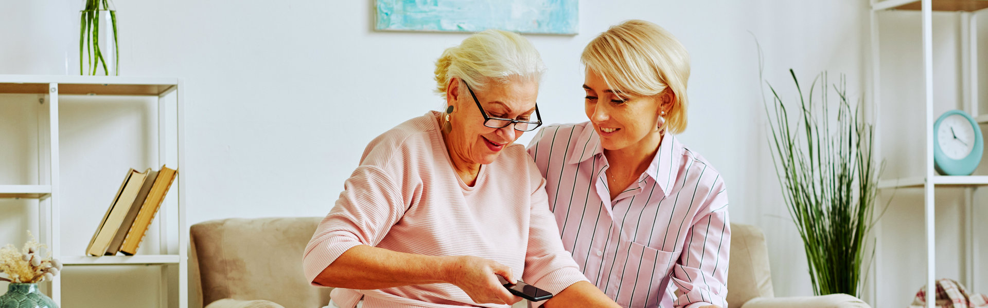 woman smiling while taking care of the senior woman