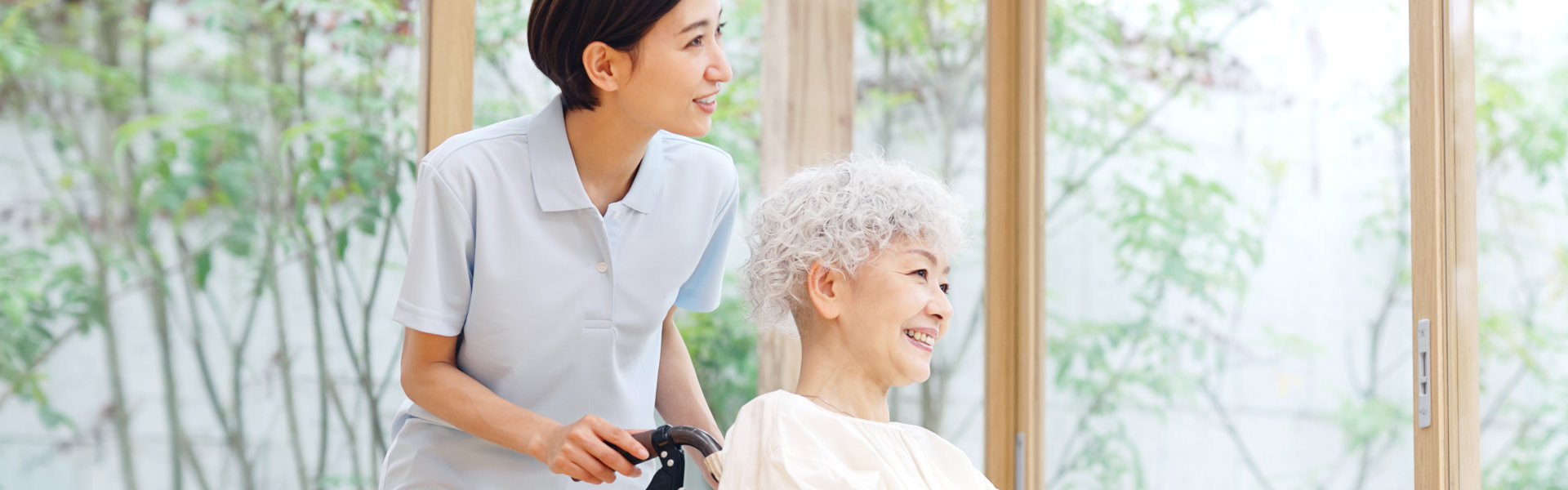 woman smiling while taking care of the senior woman