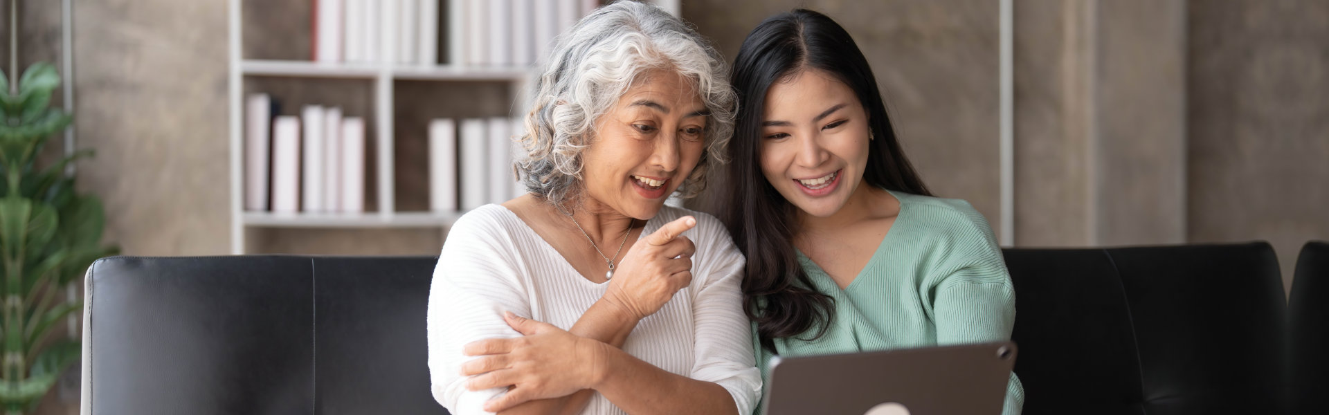 woman and senior woman smiling on the gadget they use